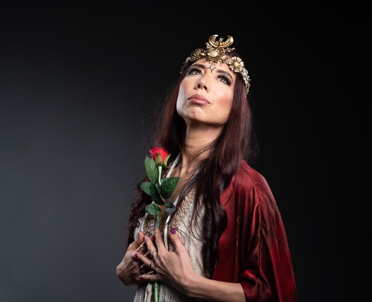 Woman in sacred attire holding a rose, symbolizing divine feminine energy and sacred sensual embodiment.